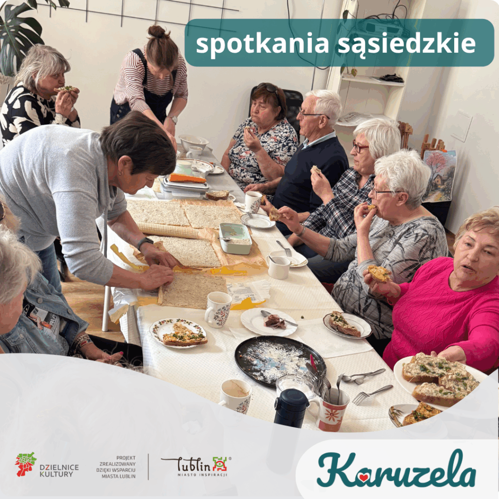 Żywiołowa grupa seniorów, zgromadzonych wokół stołu z jedzeniem. Niektórzy przygotowują jedzenie, inni jedzą lub rozmawiają. Grafika jest opatrzona napisem "spotkania sąsiedzkie".  Na dole grafiki logotypy - Karuzela, Lublin Miasto Inspiracji, Dzielnice Kultury oraz tekst "Projekt zrealizowany dzięki wsparciu Miasta Lublin" 